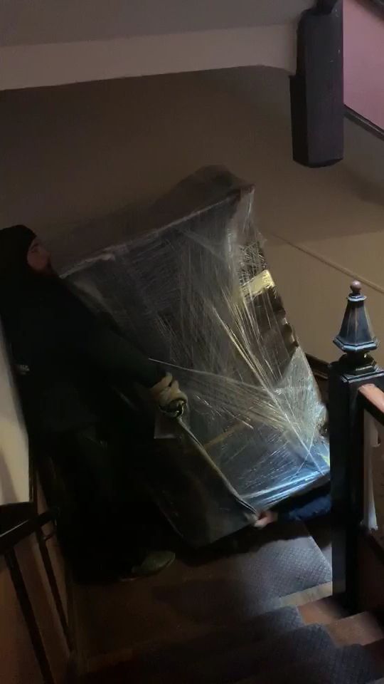 Melendez mover carrying shrink-wrapped furniture down a vintage Chicago staircase